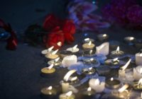 Candles and flowers at a makeshift memorial vigil at night