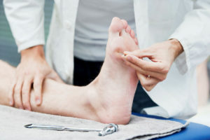 A nurse is testing the sharp sensation of the sole of a patient's foot while the patient is lying down