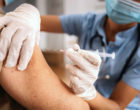 A patient receiving a vaccine injection into the upper arm from a medical professional